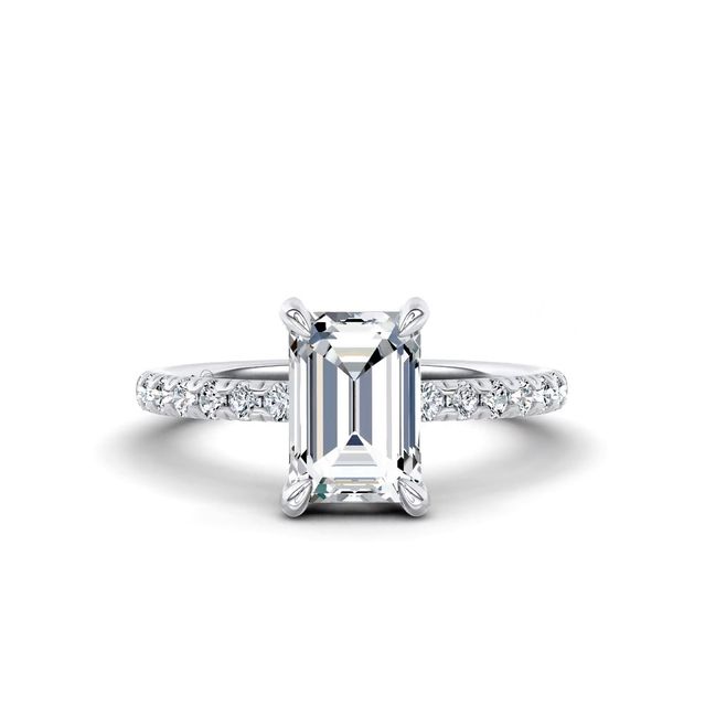 An emerald-cut diamond ring with a diamond-set band on a white background